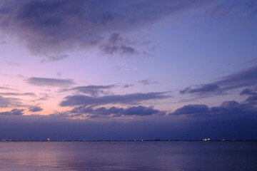 明け方の冬の海。太陽が昇りあたりはオレンジ色に染まり、水面はキラキラと輝く。兵庫県芦屋市芦屋浜で撮影。