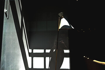 Geometric wall shadows and a tall lampshade in Central London, UK