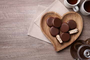 Tasty choco pies and tea on wooden table, flat lay. Space for text