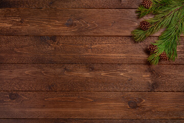 Minimal Christmas composition. Spruce branches with cones, on dark, wooden  background. Christmas, winter concept. Flat lay, top view.