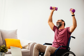 Fototapeta na wymiar Disabled Mature Man With in a Wheelchair Using Dumbbells in Order to Maintain His Physical Activity at Home in the Livingroom. Mature Man in a Wheelchair is Doing Sports, Recovery