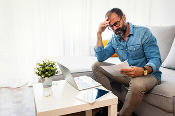 Confused frustrated mature man holding mail letter and money, reading shocking unexpected news...