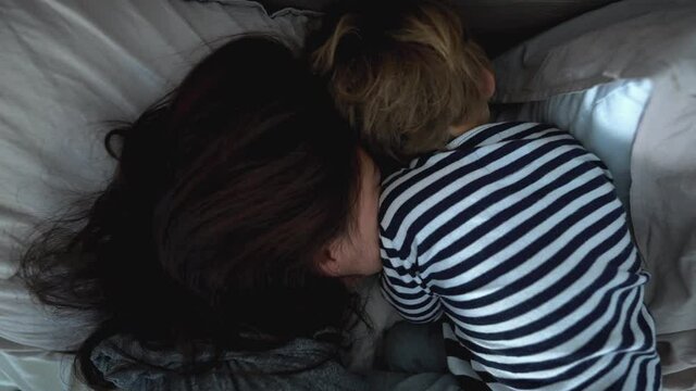 Mother and toddler child together in bed in the morning, casual family real life moment