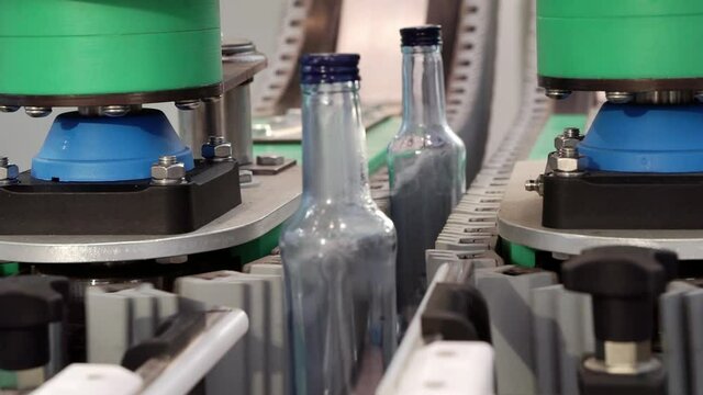 The movement of empty bottles along the conveyor belt.