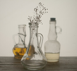 still life made through a film of glass jars with oil and dried flowers.
