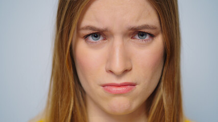 Closeup worried woman looking at camera on grey background in studio. 