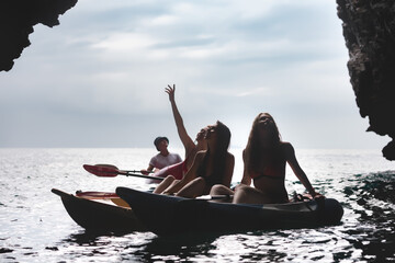 Silhouettes girls on kayaks at sea lagoon
