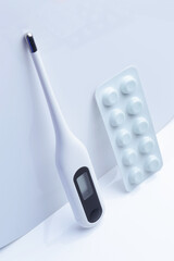 electronic thermometer and pills on a white background. concept.