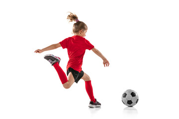 Full-length portrait of little girl, child, training, playing football isolated over white...