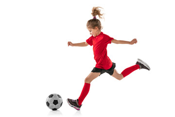 Full-length portrait of little girl, child, training, playing football isolated over white...