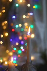 Lit candle and beautiful colorful bokeh lights. Selective focus.