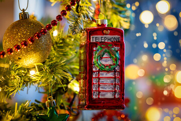 A classic, british, red telephone booth from England as a christmas ornament on a illuminated tree...