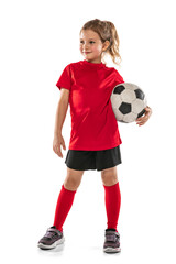 Portrait of girl, child, football player in red uniform standing with ball isolated over white...