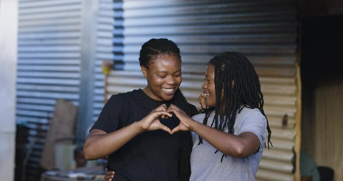 Close-up Black African female Lesbian couple showing affection in an informal settlement, South Africa