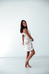 beautiful tanned woman in a summer dress with flowers in a white room