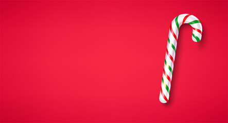 Isolated striped candy cane stick on red background.