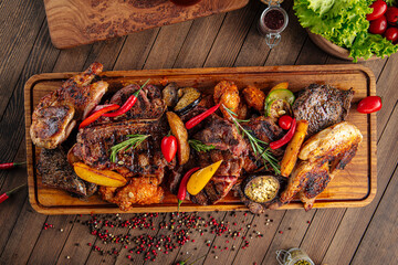 Side view on assorted grilled meat set on wooden serving board