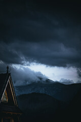 Moody mountain landscape with low clouds and hut in foreground