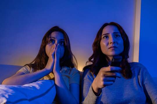 Two Girls Watching Horror Movies On Tv At Home, Two Frightened Women Watching Movies In Earnest At Night At Home