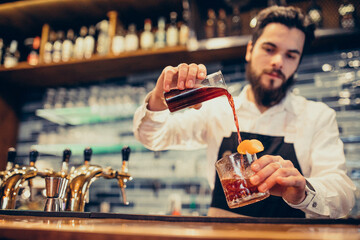 Handsome bartender making drinking and cocktails at a counter