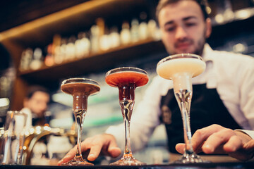 Handsome bartender making drinking and cocktails at a counter