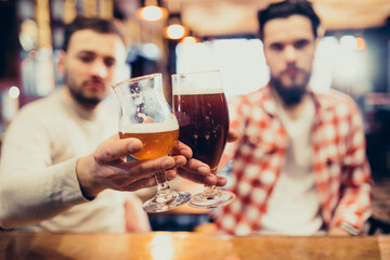 Two handsome bearded man drinking beer in pub