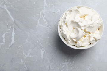 Bowl of tasty cream cheese on light grey marble table, top view. Space for text