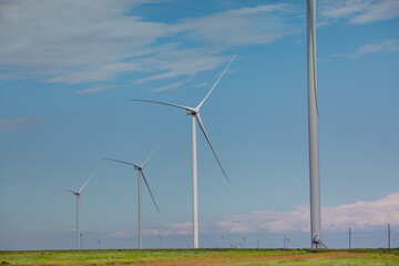 Fototapeta premium Wind turbines renewable energy source in the fields against the background of clouds