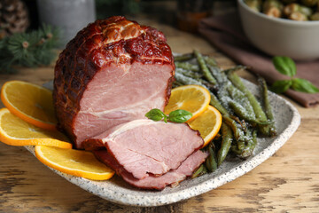 Delicious ham served with green beans and orange on wooden table, closeup. Christmas dinner