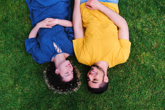 Smiling young couple lying together on grass at park