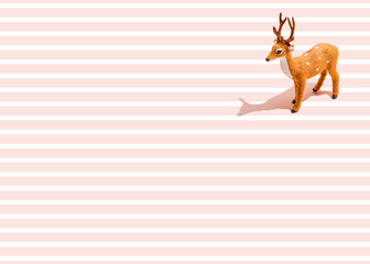 Studio shot of reindeer figurine standing against pink striped background
