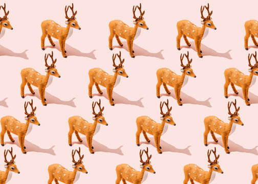 Pattern of reindeer figurines standing against pink background