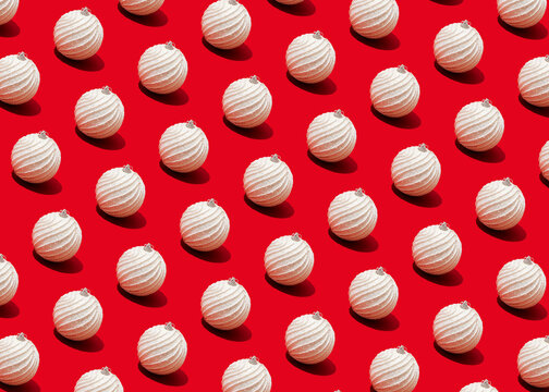 Pattern ofwhite-coloredChristmas ornaments flat laid against vibrant red background
