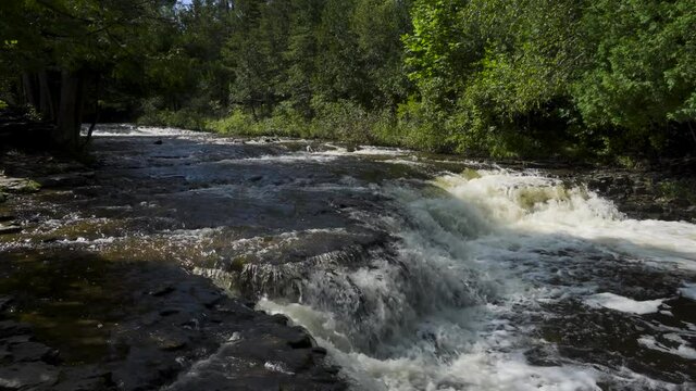 River water flowing over the rocks; Ocqueoc Falls, rushing water over layers of rocks in Northwest Michigan after months of rain in late summer--late morning. 444
