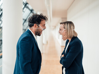Male and female partners with face masks screaming at each other in office