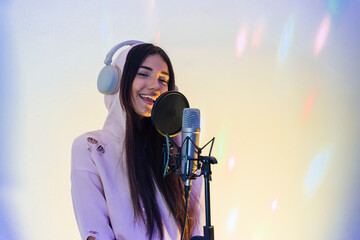 Smiling female singer wearing hooded top singing at studio