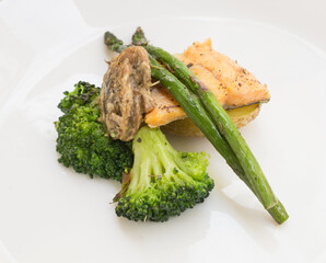 dish of trout fillet, broccoli, asparagus sprouts and sauce on a white plate