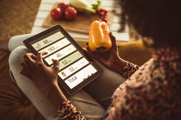 Woman planning diet through digital tablet at home