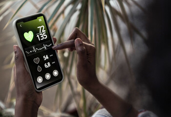 Woman checking pulse trace through mobile phone at home