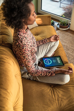 Woman meditating while sitting with timer on digital tablet at home