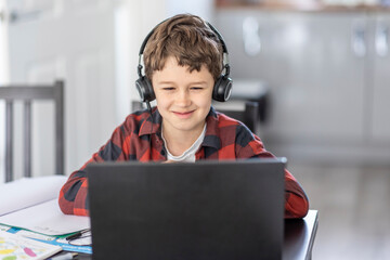 Smiling boy attending online classes through laptop while e-learning at home