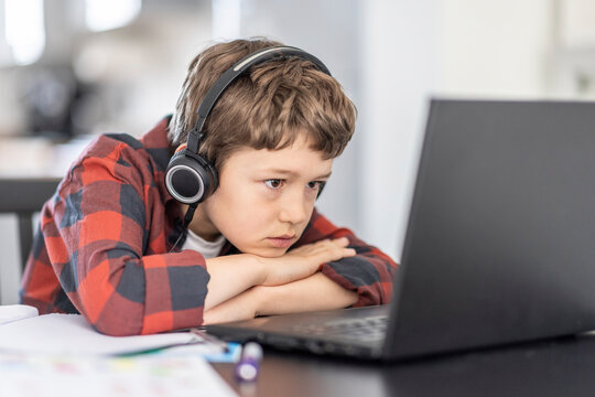 Boy attending online classes through laptop while e-learning at home