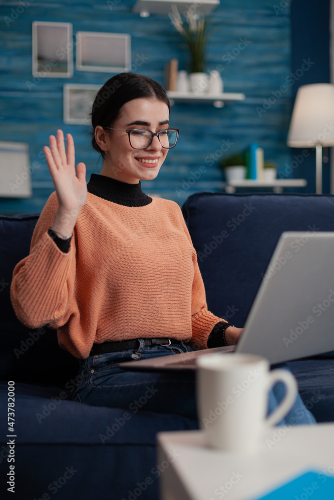Aufkleber smiling student on sofa with laptop on lap waving hello in videocall. programmer with glasses sittin