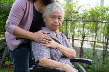 Caregiver daughter help Asian senior or elderly old lady woman on electric wheelchair in park.