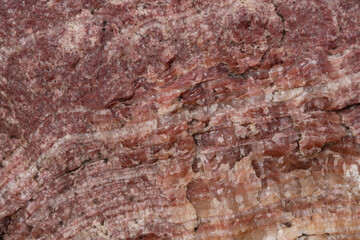 The texture of a red mineral. Gneiss rock. Layers. Selective focus.