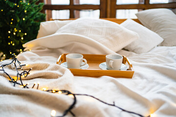 A wooden tray for eating in bed with two white tea cups. 