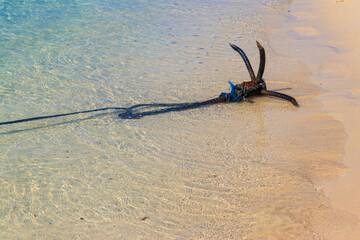 Small boat anchor on a shore of ocean