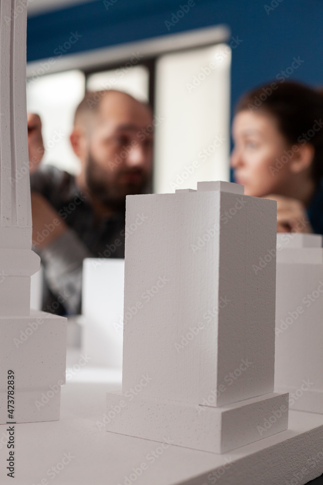 Poster closeup of white foam architectural scale model of residential building complex in front of architec