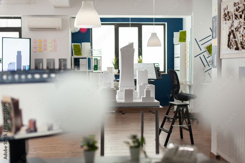 Poster empty architectural office with foam building model on table and computer screen with blueprints. no