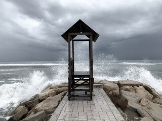 Stormy sea, wooden view point to the sea, gray sky, windy weather at the sea